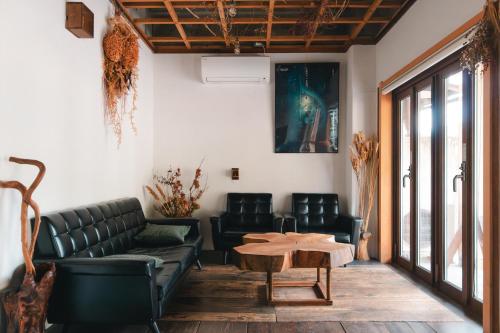 ein Wohnzimmer mit schwarzen Ledermöbeln und einem Tisch in der Unterkunft MOUNTAinn Nagiso in Nagiso
