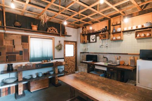 eine Küche mit einem Holztisch und einem Kühlschrank in der Unterkunft MOUNTAinn Nagiso in Nagiso