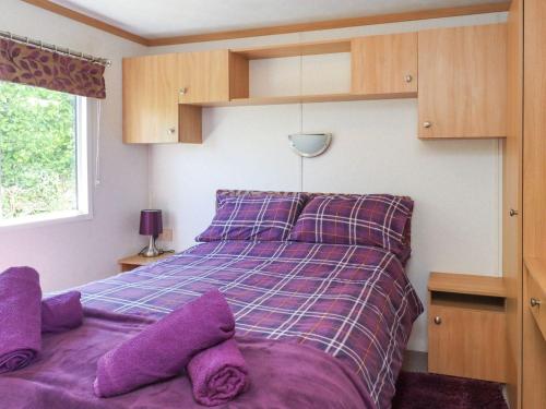 a bedroom with a purple bed with purple pillows at The Lodge Caravan Rental in Amlwch