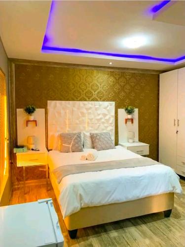 ein Schlafzimmer mit einem großen Bett mit violettem Licht in der Unterkunft A & A Hotel in Lungi