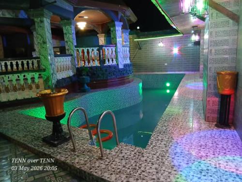 ein Schwimmbecken mit grünen und violetten Lichtern in der Unterkunft A & A Hotel in Lungi
