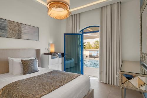 a bedroom with a bed and a door to a pool at Santorini check in in Ras al Khaimah