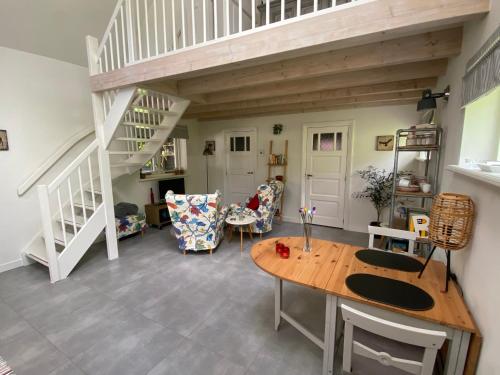 a living room with a wooden table and stairs at UNIEK Bommelgaard, guesthouse in het prachtige Rivierenland! in Hurwenen