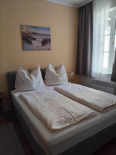 a bedroom with a bed with white sheets and pillows at Ferienwohnung DuO in Stubenberg