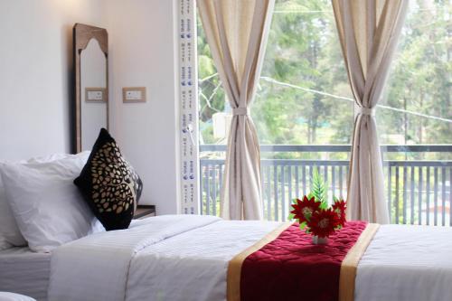 a bedroom with a bed and a large window at Altiora Homestay in Kodaikānāl