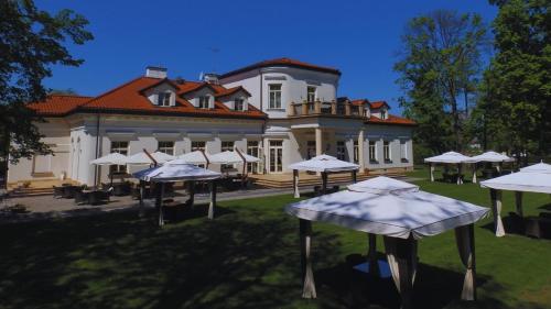 a large building with tables and umbrellas in front of it at Pałac Żelechów Spa & Wellness in Żelechów