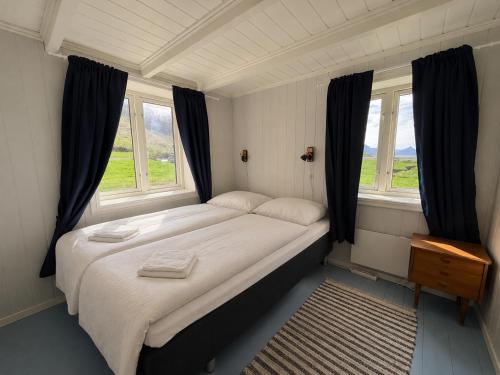 a bedroom with a large bed with two windows at The Haukland House, Between Peaks & Sea in Leknes