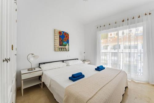 a white bedroom with a bed with blue towels on it at Edf España Suites Mijas in Mijas