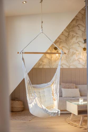 a hammock hanging in a room with a bed at Appart'Hôtel & Spa "Les Voiles" Le Molène in Carnac