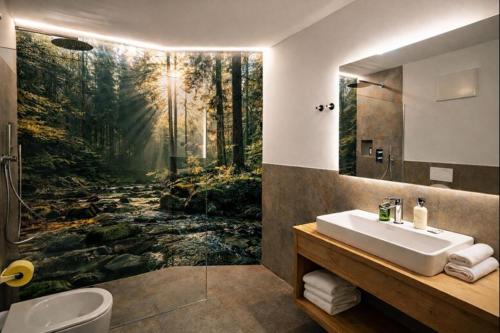 a bathroom with a painting of a forest at Binterhof in Castelrotto