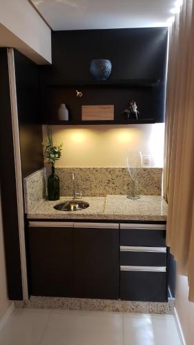 a kitchen counter with a sink in a room at Lindo Studio no Centro de Poços de Caldas in Poços de Caldas