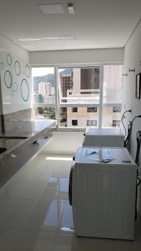 a white room with a large window and a suitcase at Lindo Studio no Centro de Poços de Caldas in Poços de Caldas