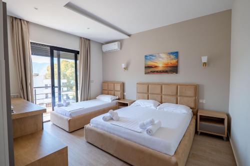 a hotel room with two beds and a balcony at Hotel Roalb in Vlorë