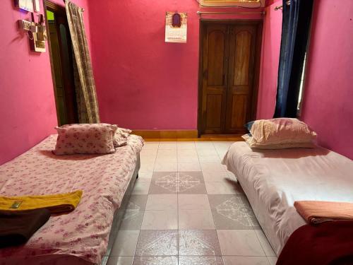 two beds in a room with pink walls at Real City Homestay in Guwahati