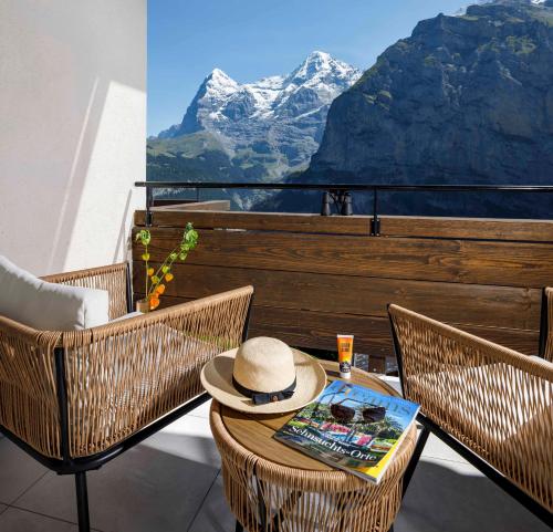 a table with a hat on top of a balcony at Eiger Mürren Swiss Quality Hotel in Mürren
