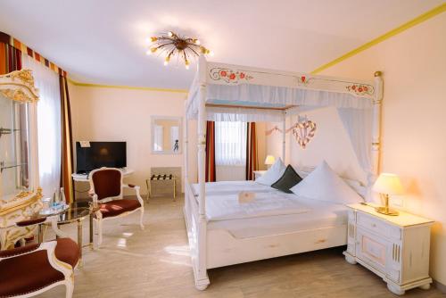 ein Schlafzimmer mit einem weißen Himmelbett und ein Wohnzimmer in der Unterkunft Hotel Speeter in Weisenheim am Berg
