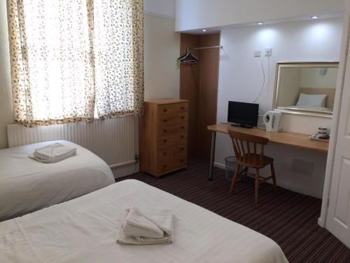 a hotel room with two beds and a desk and a mirror at Lockyer House B&B in Plymouth