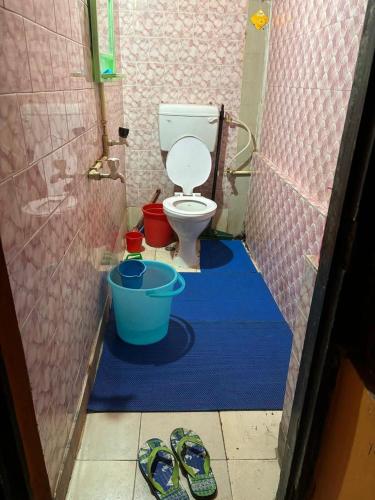 a bathroom with a toilet and a pair of slippers at Real City Homestay in Guwahati