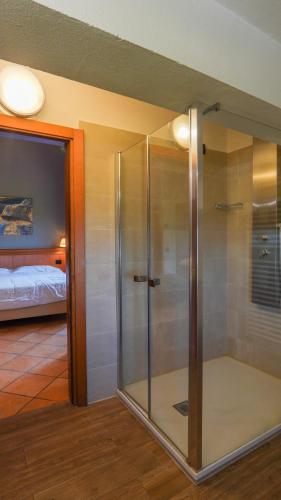 a glass shower in a room with a bedroom at Locanda La Scottiglia in Seggiano