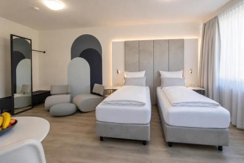 a hotel room with two beds and a table at zzzpace Smart-Hotel Bielefeld Zentrum in Bielefeld