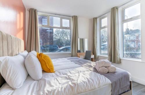 a bedroom with a large white bed with windows at Mauldeth Shared House in Manchester