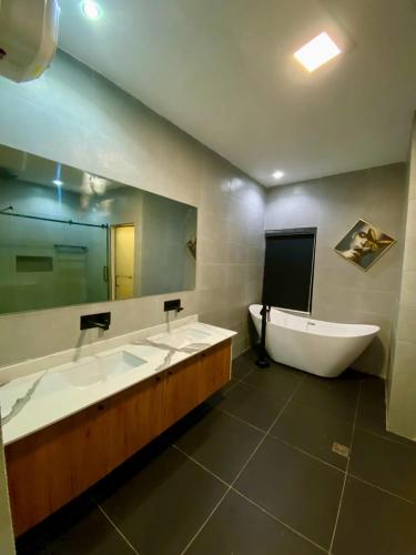 a bathroom with three sinks and a tub and a mirror at The Crest Triplex in Ikeja