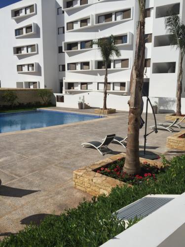 a hotel with a palm tree and a swimming pool at Iken Park Agadir in Agadir
