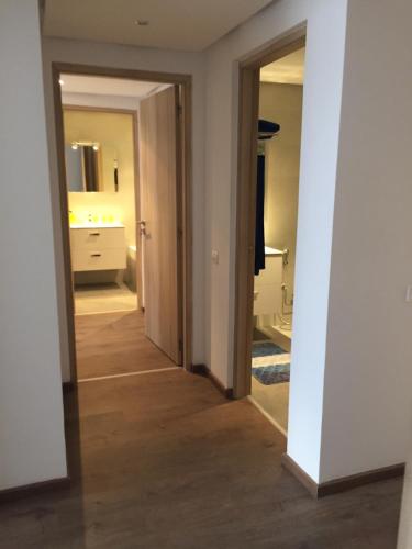 a hallway leading to a bathroom with a sink and a mirror at Iken Park Agadir in Agadir