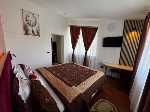 a hotel room with a bed and a desk at Pensiunea Doina Sacele in Săcele