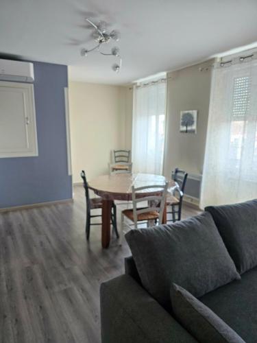a living room with a couch and a table and chairs at Les Trésors à 2 pas du Pal in Dompierre-sur-Besbre