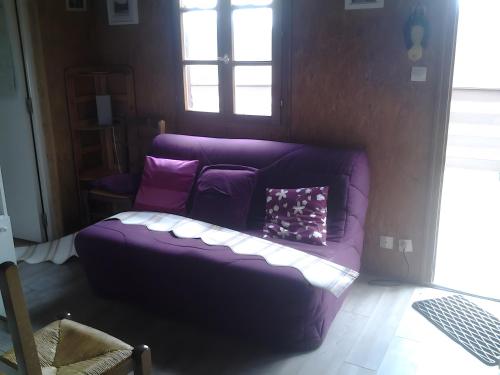 a purple couch in a living room with a window at Le Chalet De Pierre Sèche in Chaumard