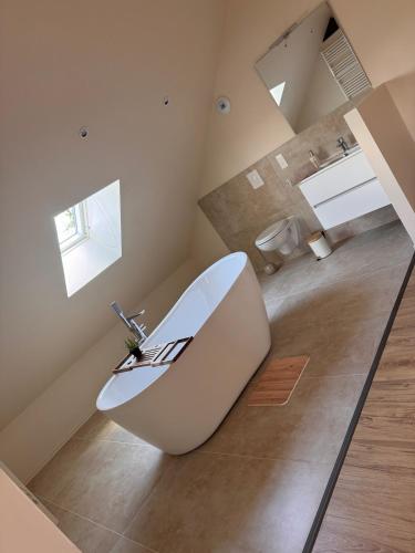 a large white tub in a bathroom with two windows at Sous les combles in Hambach