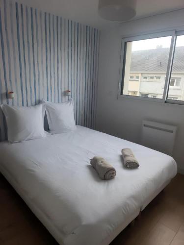 a white bed with two pillows on it with a window at Maison près de la plage in Sangatte