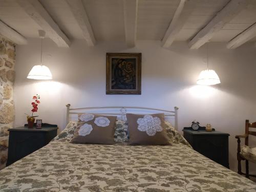 a bedroom with a bed with two night stands and two lights at Cozy stone house in Sikéa