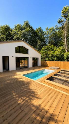 a house with a swimming pool and a wooden deck at La Villa Véga 8 pers in Martillac