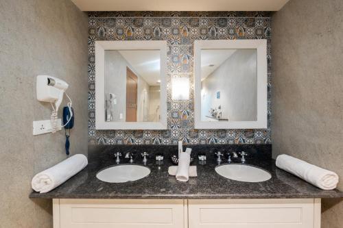 a bathroom with two sinks and two mirrors at The Ivy Anjuna in Anjuna