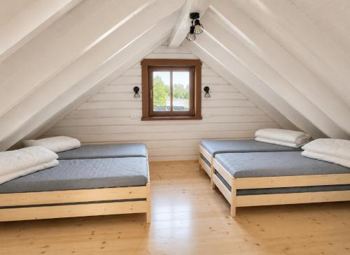 two beds in a attic room with a window at KOPUVA seaside villas in Nida