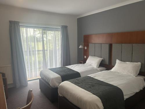 a hotel room with two beds and a window at Crossroads by Chef & Brewer Collection in Weedon Bec