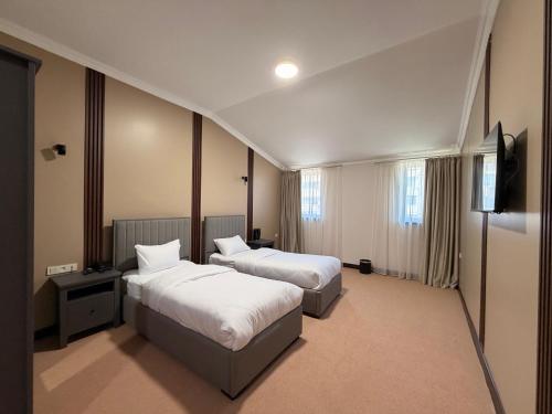 ein Hotelzimmer mit zwei Betten und einem Fernseher in der Unterkunft Sheldon Hotel in Yerevan