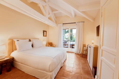 a bedroom with a white bed and a window at La Bastide de Saint Tropez in Saint-Tropez