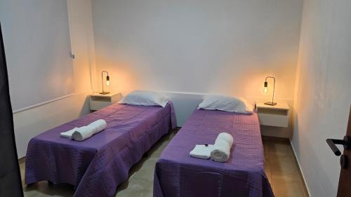 two beds in a room with purple sheets at Moderno apartamento en Colón in Colón Buenos Aires Province