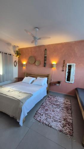 a bedroom with a large bed and a pink wall at Morada Palmeira Real Peruibe - SP in Peruíbe