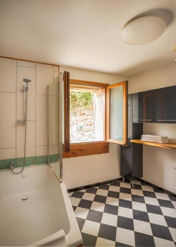 a bathroom with a tub and a window and a checkered floor at The Dragon Barn - Grenier in Ascou