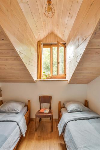 two beds in a small room with a window at The Dragon Barn - Grenier in Ascou