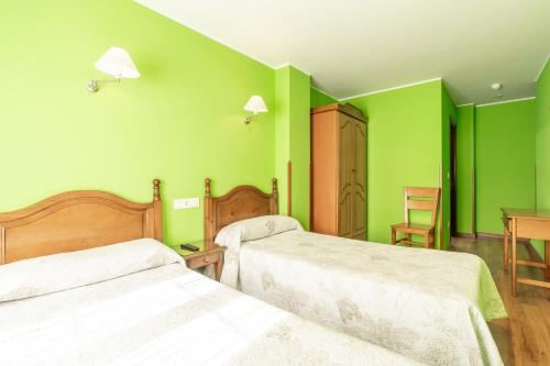 a green room with two beds and a table at Pension Monteverde in Cangas de Onís