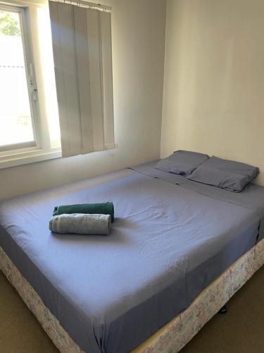 a bed with a green towel on top of it at Girrawheen3 - Room in a Shared House in Perth