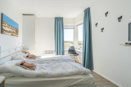 a bedroom with a large bed with blue curtains at Appartementencomplex Juliana 132 in De Koog