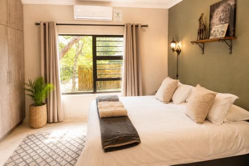 a bedroom with a large white bed with a window at Maningwe in Marloth Park