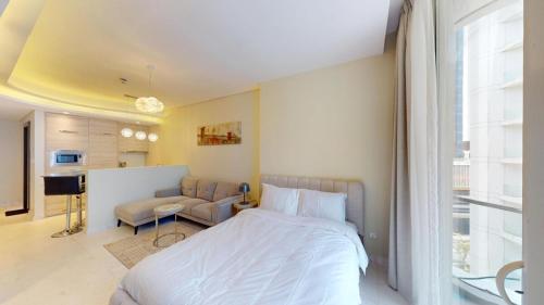 a bedroom with a bed and a couch and a window at Bahrain Bay Retreat Studio in Manama