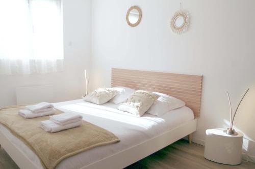 a white bedroom with a bed with white towels on it at Les Coquelicots - Parking privé, Terrasse, Clim, Netflix, Au Calme in Hem-Lenglet